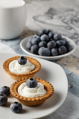 tartlets with cream and blueberries on the table, selective focus