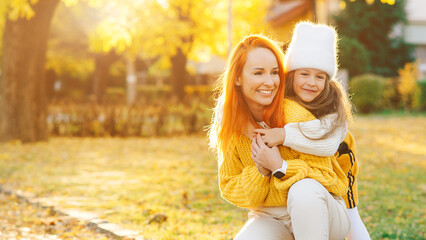 Stylish family on autumn walk. Mother and daughter walking in the park. Mom and child having fun together.