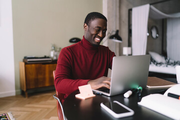 Happy black man working on laptop at home