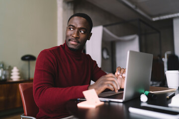 Pensive black man surfing netbook at home