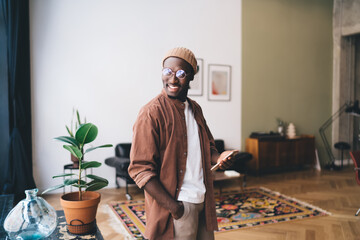 Cheerful black man in eyeglasses standing with smartphone
