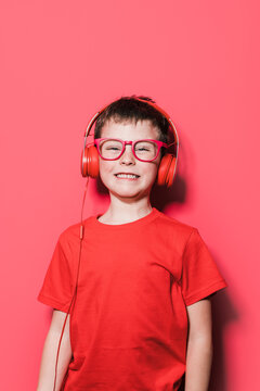 Smiling Kid With Headphones Standing Against Red Background