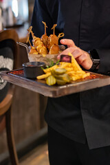 Waiter hold plate with corn dog in pub