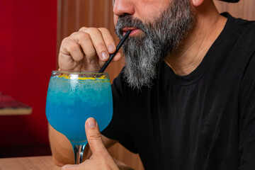 hombre barman con gorro de vaquero preparando un cóctel azul en la barra del bar