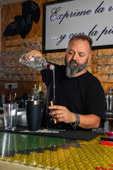 hombre barman con gorro de vaquero preparando un cóctel azul en la barra del bar