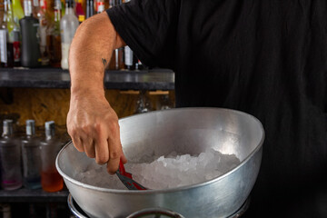 hombre barman con gorro de vaquero preparando un cóctel azul en la barra del bar