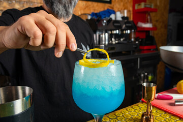 hombre barman con gorro de vaquero preparando un cóctel azul en la barra del bar