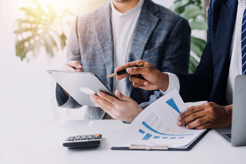 Financial analysts analyze business financial reports on a digital tablet planning investment...