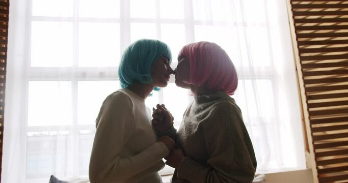 Couple, lgbt and lesbian women at home. Embrace and holding each other. Love and kiss, Pride Event, friendship concept. Romance and portrait of lesbian couple with blue and pink hair enjoying.