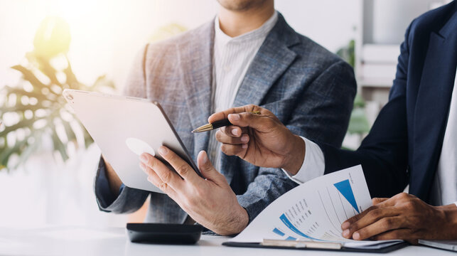 Financial analysts analyze business financial reports on a digital tablet planning investment project during a discussion at a meeting of corporate showing the results of their successful teamwork.