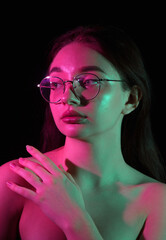 Portrait of a girl in glasses with color lighting on a black background. Dual color lighting