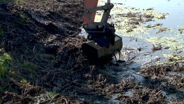 excavator dredge is dredging, working on river, canal, deepening and removing sediment, mud from riverbed in a polluted waterway.
Large excavators engaged in cleaning of the riverbed of a river from t
