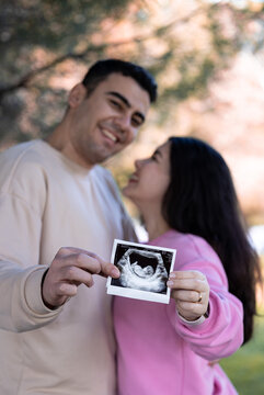 Pregnancy announcement concept. Wife and husband holding ultrasound picture of their future baby.