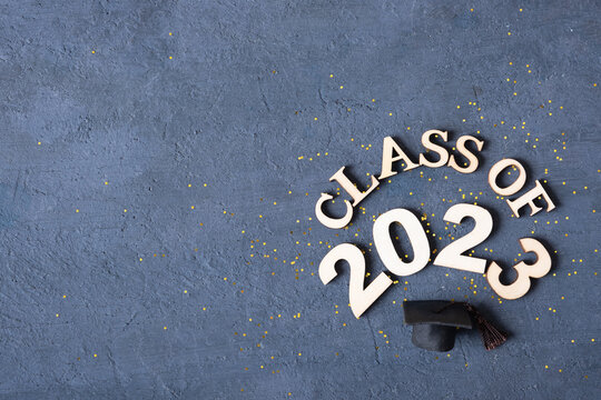 Class of 2023 concept. Wooden number 2023 with graduate statuette on concrete background with tinsel top view