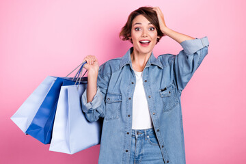 Photo of excited cute woman wear jeans shirt arm head rising shoppers isolated pink color background