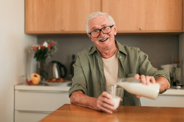 Portrait of senior man sitting in kitchen and pouring milk in his glass. Healthy lifestyle concept.