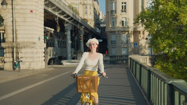 Happy woman riding a yellow bicycle on a bridge in Paris