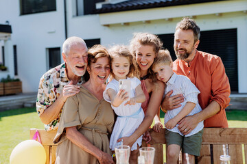 Multi generation family taking selfie on backyard in summer during garden party.