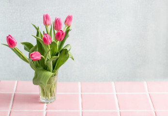 Spring emote table background.  vase with pink tulips with space. Home interior decoration, minimalist design or springtime holidays. 
