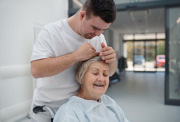 Obraz premium Young man with down syndome working in hospital as caregiver. Concept of integration people with disability into society.