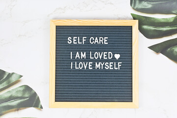 Grey letter board with phrase Self care, I am loved, I love myself. Self love, Mindfulness...