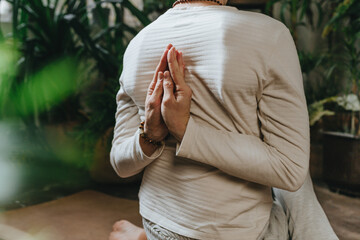 Back view of yoga male instructor joining hands together