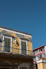 Obraz premium Shabby yellow facade with windows closed by shutters.