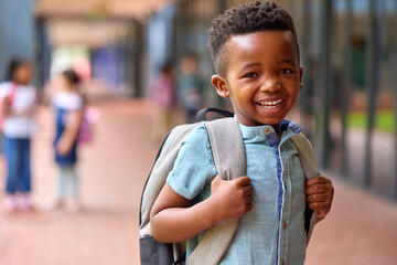 Portrait Of Smiling Male Elementary School Pupil Outdoors With Backpack At School - Powered by Adobe