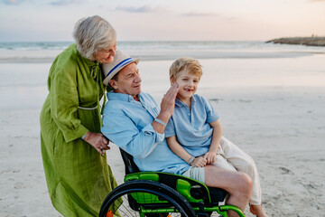 Little boy with his granfather on wheelchair, having fun and enjoying sea together.