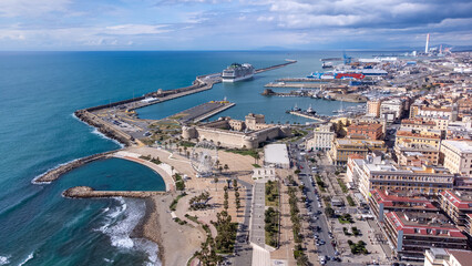 Panoramic view of the city of Civitavecchia with the adjoining tourist port and Forte Michelangelo. Emerald sea and view with tropical palm trees. Ferris wheel and cloudy sky.