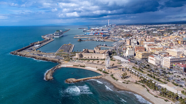 Panoramic view of the city of Civitavecchia with the adjoining tourist port and Forte Michelangelo. Emerald sea and view with tropical palm trees. Ferris wheel and cloudy sky.
