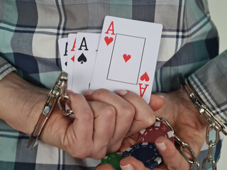 Handcuffed hands with playing cards and casino chips