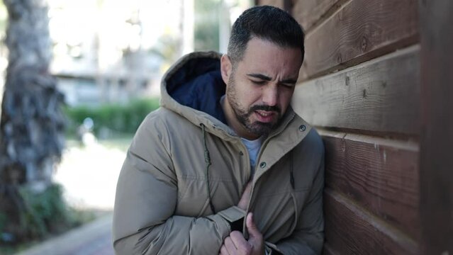Young hispanic man suffering heart attack at street