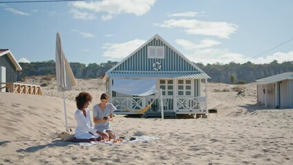 Happy girls checking social media smartphone at beach houses. Two friends rest - Powered by Adobe
