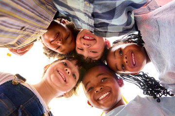 Low Angle Portrait Of Smiling Multi-Cultural Children Looking Down Into Camera