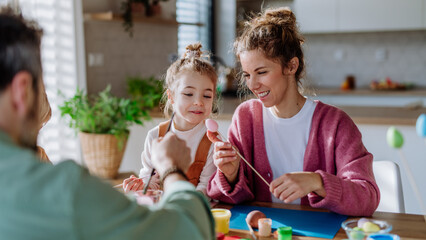 Happy family with little child decorating easter eggs.