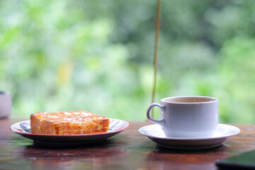 cup of coffee and toasted bread on the wooden table with a garden view