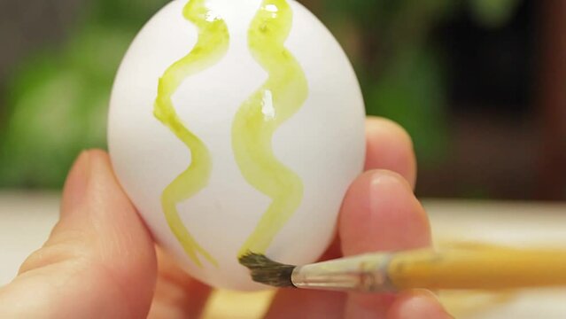 We paint the Easter egg with a brush in bright colors. Religion concept, Easter.