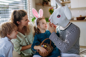 Little children having fun with her mother and Easter rabbit, celebrating Easter.