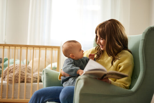 Mother showing images in a picture book to her cute little son