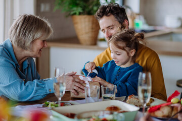 Little girl unwraping gift at family dinner.