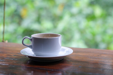 cup of coffee and toasted bread on the wooden table with a garden view