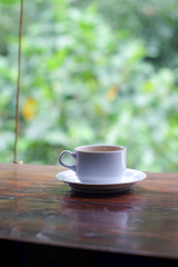 cup of coffee and toasted bread on the wooden table with a garden view