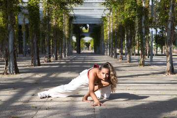 Latin woman, young and beautiful dancing modern dance in the street in a park and makes different...