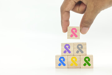 World breast cancer day, hand picking up wooden cube block with pink color ribbon icon on white background, breast cancer awareness,Healthcare and medical concept.