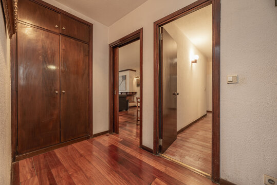 Entrance hall of a house with a built-in wardrobe with dark wooden doors, red wooden floors and matching doors