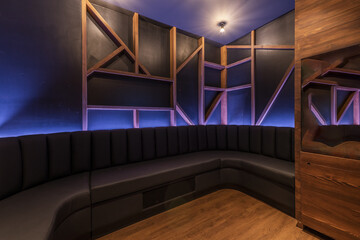 Empty karaoke room with perimeter sofa and wooden decoration
