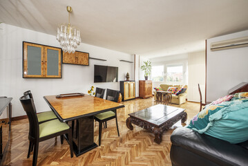 Living room of a house with wooden furniture of different styles poorly combined and sofas of the same style