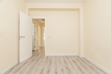 Empty room of an apartment with white wooden doors and skirting boards, a light wooden floor and cream painted walls