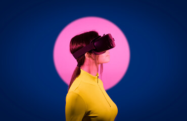 Woman watching on virtual reality goggles by pink light over black background
